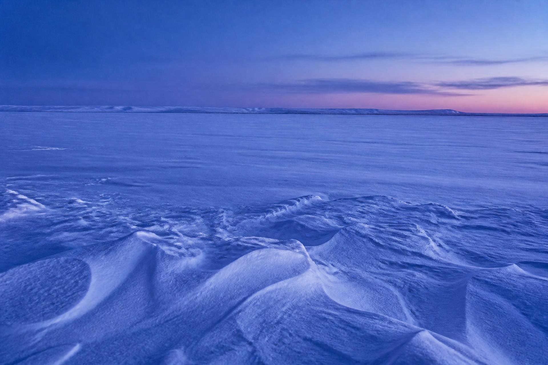Snow-covered open land at blue hour